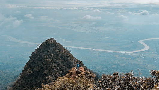 Man in Blue on Top of the Mountain With Areal View thumbnail
