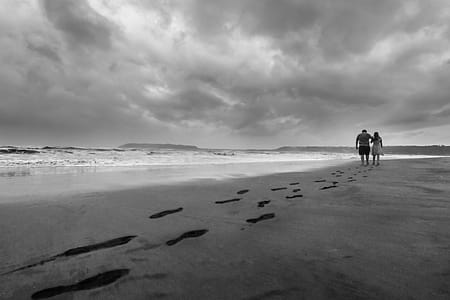 Grayscale Photo of Couple Walking on Seashore thumbnail