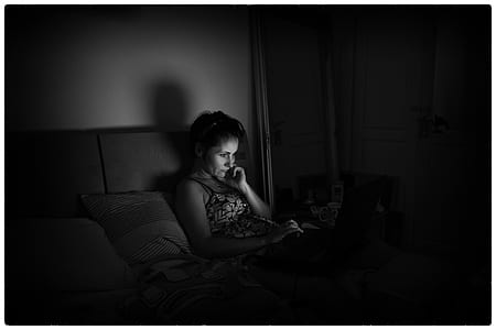 grayscale photograph of woman lying on bed using laptop thumbnail