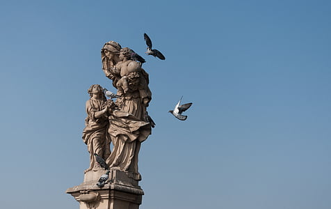 bird about to land on family of three statue thumbnail