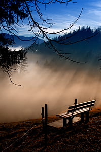 gray wooden bench on top of the mountain range overlooking the fog thumbnail