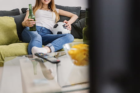 Very excited young woman watching football sport on tv at home. thumbnail