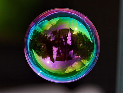 round iridescent bubble showing a reflection of trees thumbnail