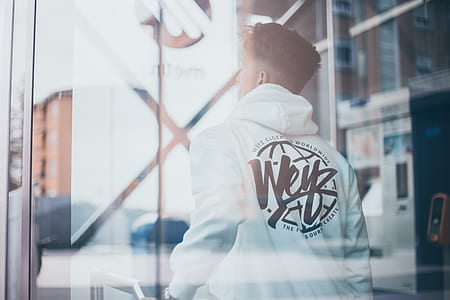 man in white and black hoodie standing near automated teller machine thumbnail