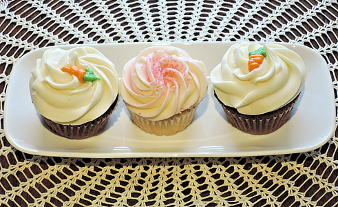 three white icing-covered cupcakes on white ceramic dish thumbnail