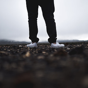 person in black pants wearing white Converse low top sneakers in tilt shift photography thumbnail