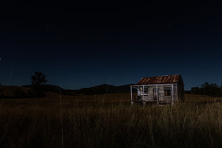 gray and brown wooden house in middle of grass field thumbnail