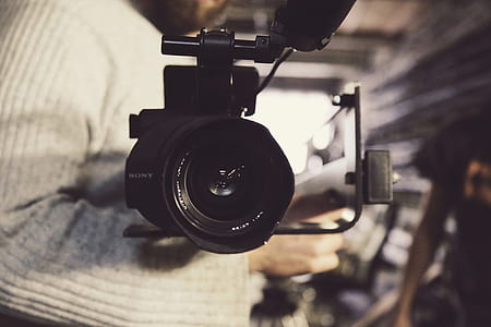 selective focus photography of camcorder beside man's arm thumbnail