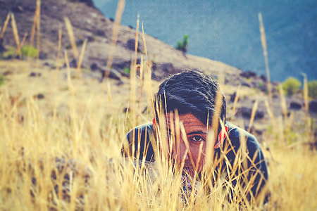focus photo of man in black shirt on dried grass field thumbnail