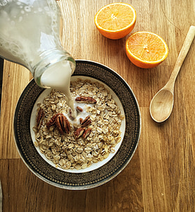 oatmeal with wallnuts inside bowl on beside sliced orange fruits photography thumbnail