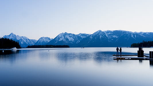 landscape photography of 2 person standing on dock during daytime thumbnail