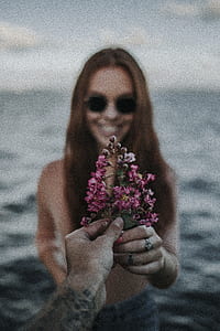person and woman holding pink flower selective focal photo thumbnail