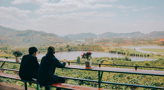 Two Person Sitting on Chair in Front of Lake and Mountains thumbnail