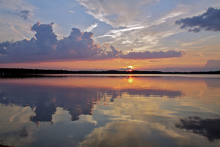 silhouette photo of body of water under white clouds and blue sky thumbnail