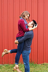 man carrying a woman ner red wall thumbnail