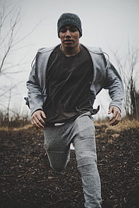 man running on brown soil near bare trees thumbnail