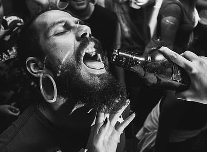 Person Holding Bottle in Front of Man's Mouth thumbnail