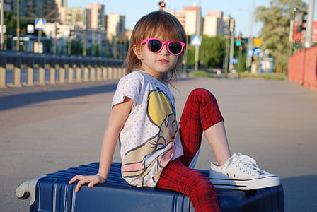 girl sitting on hardside luggage bag thumbnail