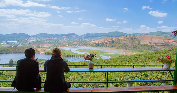 Two Men Sitting On Table Facing Lake thumbnail