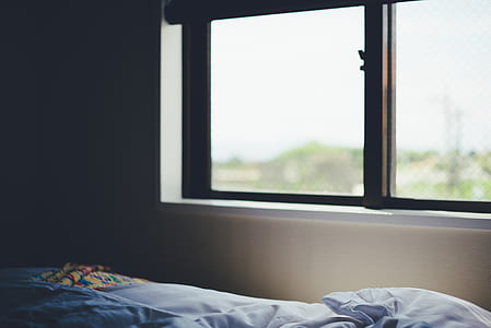 blue bedspread near brown framed glass window closed thumbnail
