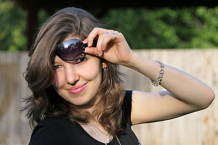 smiling woman holding black framed sunglasses thumbnail