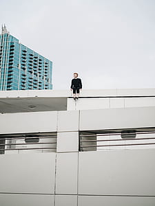 man sitting on the edge of the building in worm's eyeview photography during daytime thumbnail