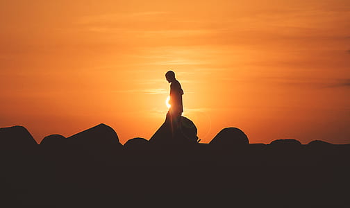 silhouette of a person near rock at golden hour thumbnail