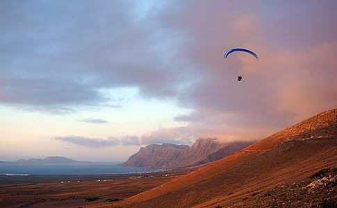 person with parachute going down on hill during sunset thumbnail