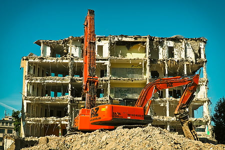 red backhoe near wrecked building thumbnail