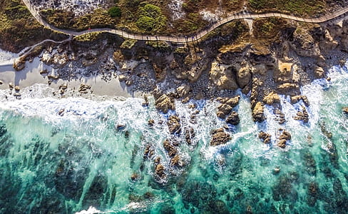 aerial photo of sea waves in front of rock formation thumbnail