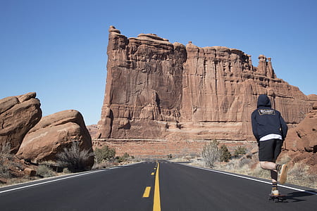 man roller skating on asphalt road near boulders thumbnail