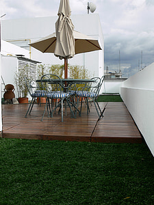 round gray metal patio dining set with parasol beside white concrete fence thumbnail