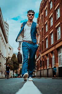 man walking on road between building under cloudy sky during daytime thumbnail