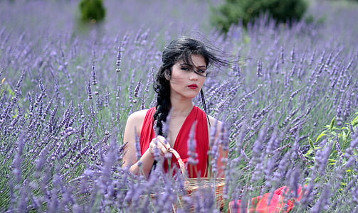 woman wearing red sleeveless top surrounded by purple petaled flowers thumbnail