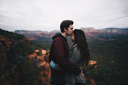 man kissing woman's forehead at top of mountain beside range thumbnail