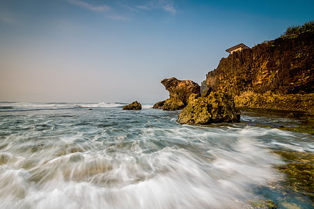 photo of brown mountain near beach at daytime thumbnail