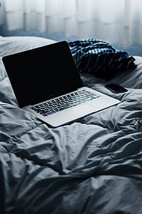 turned off black laptop computer on gray comforter thumbnail