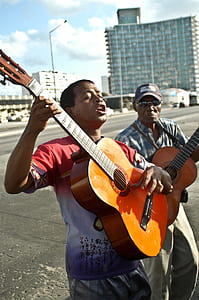 man playing brown acoustic guitar during daytime thumbnail