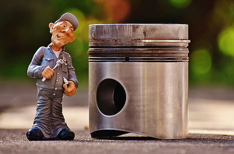 selective focus photography of male mechanic figurine beside gray metal pistol on gray pavement thumbnail