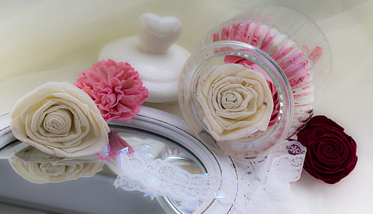 white and pink petaled flower on mirror near clear glass jar thumbnail