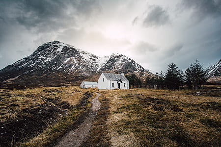 white and black 1-storey house near mountains under nimbus clouds thumbnail