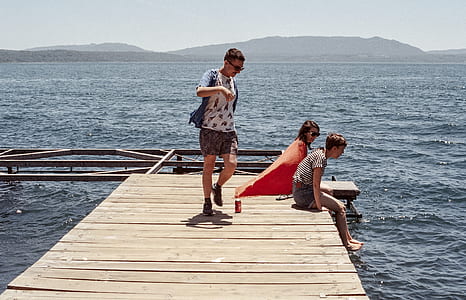man standing on dock with two women thumbnail