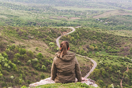 woman sitting on edge of cliff looking at road on plateau thumbnail