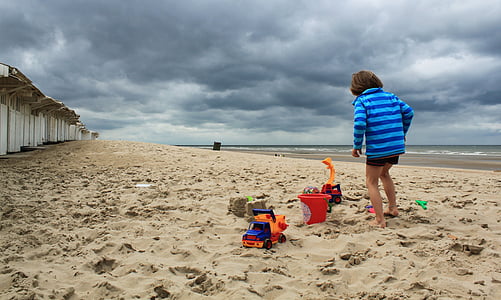 person standing on sea shore under gray sky thumbnail