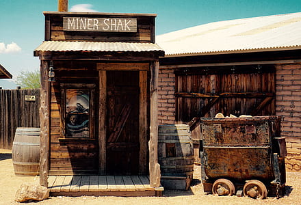 brown wooden miner shack near brown tunnel cart and log cabin at daytime thumbnail