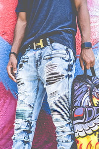 man holding backpack white leaning on painted wall thumbnail