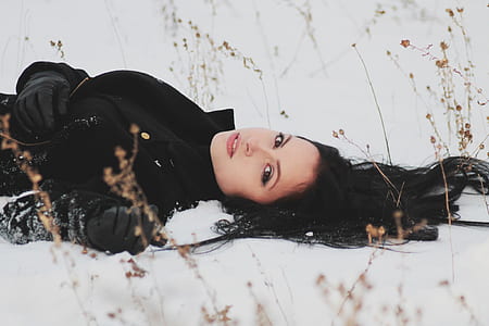 woman wearing black coat laying on snow field thumbnail