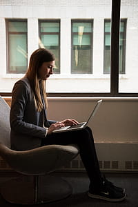 Woman Sits and Use Laptop Computer Near Window thumbnail