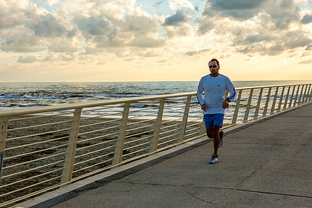 man in blue long-sleeved shirt jogging during daytime near body of water thumbnail