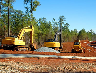 yellow excavator near green trees during daytime thumbnail